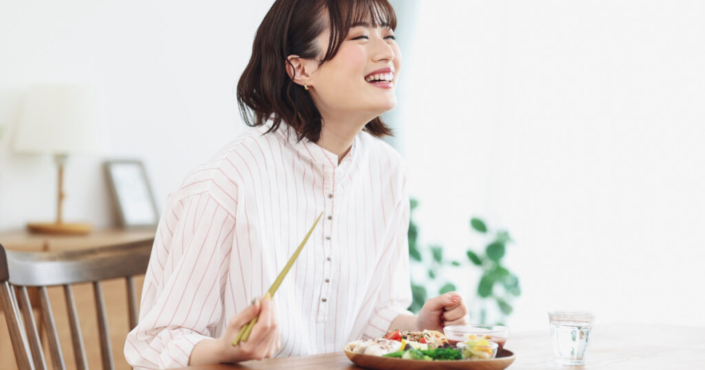 A woman is eating with a smile